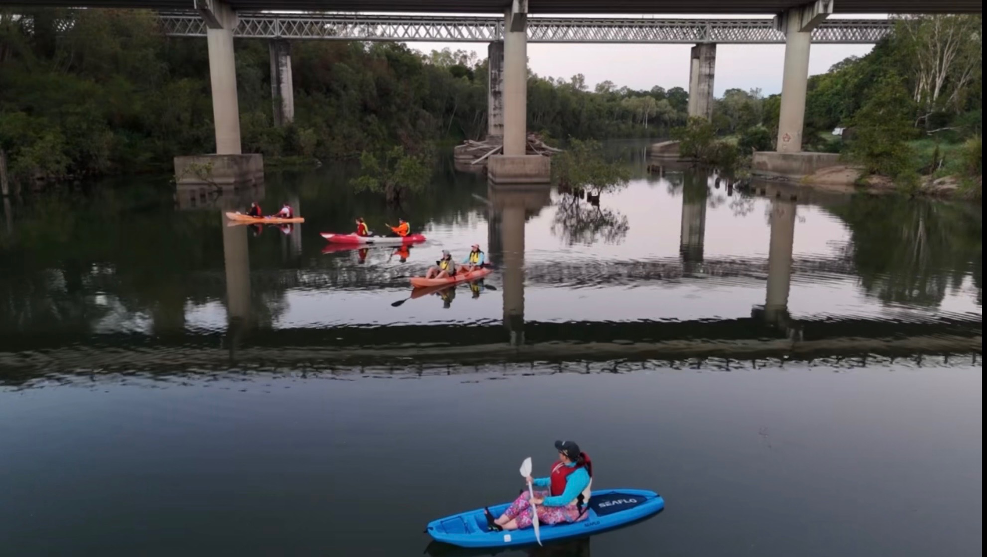 Kayakers paddling beneath the Pioneer River bridges