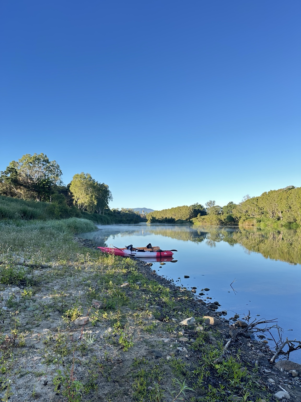 Kayaks resting beside a calm Pioneer River